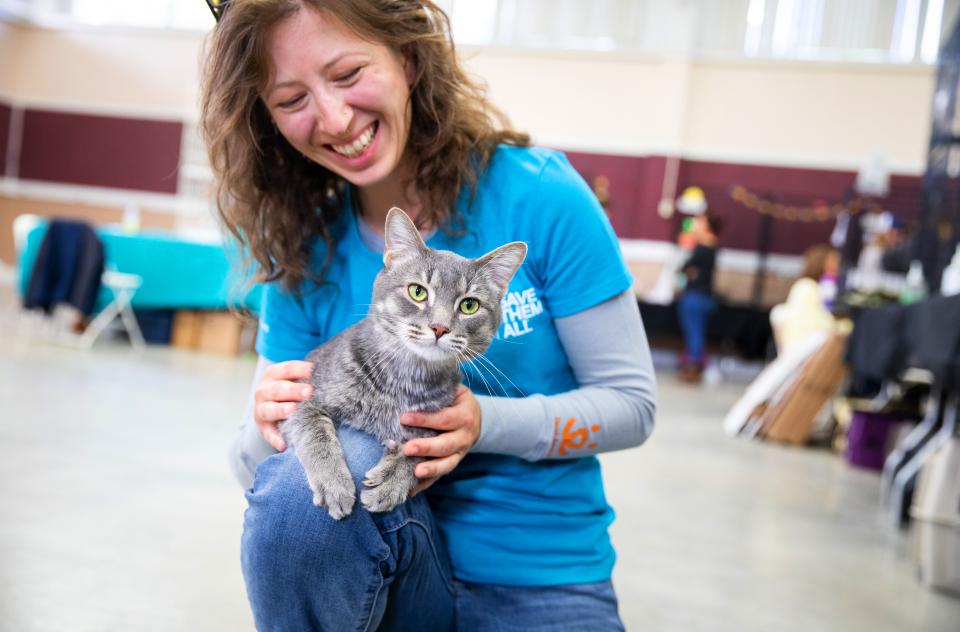 Smiling person holding a cat on their lap at a pet adoption event