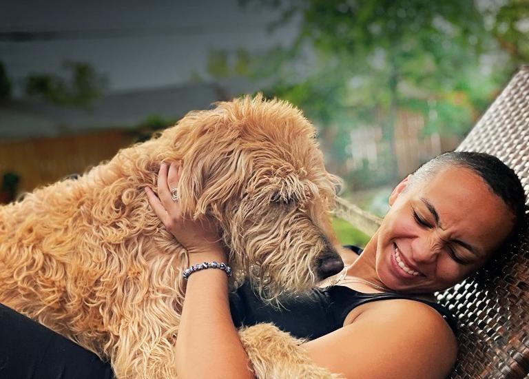 Woman smiling and cuddling large fluffy brown dog