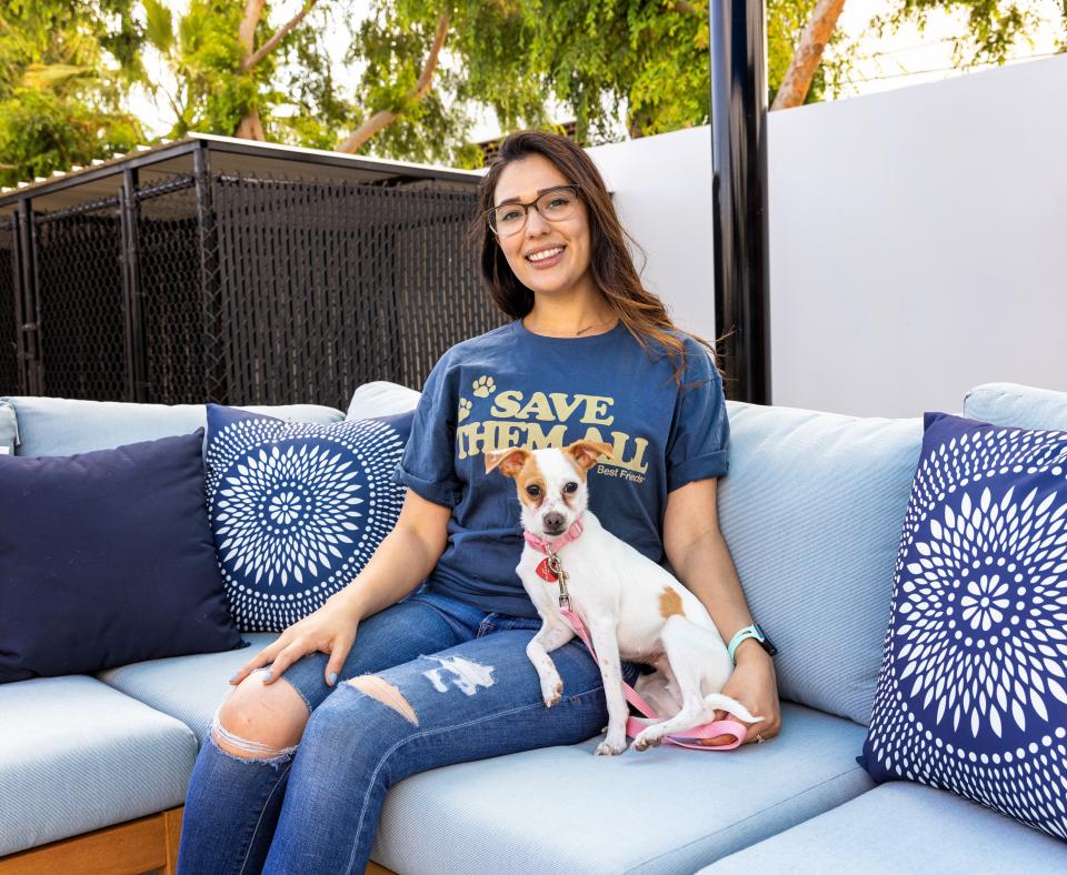 Smiling person wearing a "Save Them All" t-shirt while sitting with a dog outdoors with a small dog