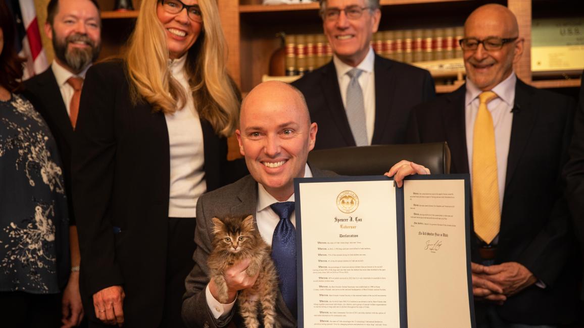 The governor of Utah, Gov. Spencer Cox, holding the written declaration as well as a kitten with Best Friends CEO Julie Castle behind him
