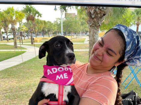 Best Friends marketing intern Jazmin Aguilar holding a dog wearing a pink Adopt Me bandanna
