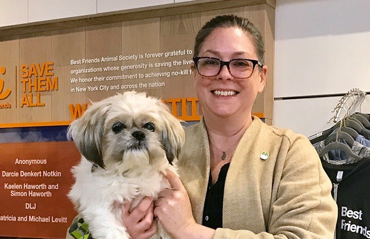 Smiling woman holding the small fluffy dog she's adopting
