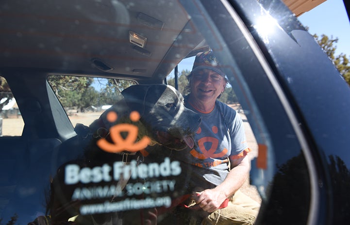 Dogtown caregiver Tom putting Jango the dog into a car with a Best Friends decal