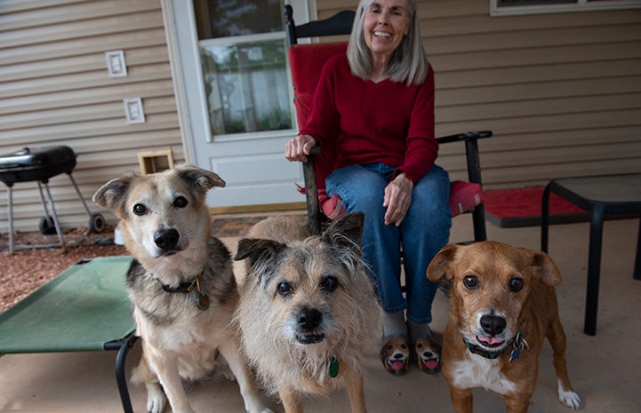 Fredi Miller, a local volunteer. sitting on a chair on her porch with her two dogs and Benjamin the dog who she's fostering