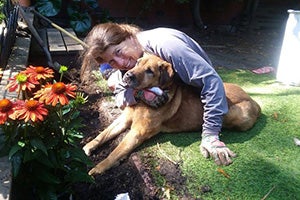 Tammy Hilbrich and Spartacus the dog snuggling on a lawn