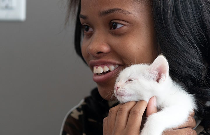 Smiling young girl holding a white kitten