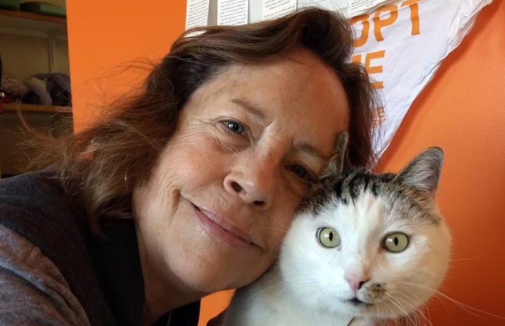 Cat World volunteer coordinator Teresa with her face next to Paytrix the cat