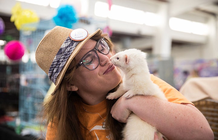 Woman wearing a hat holding a white ferret named Draco Malfoy at the May the 4th NKUT Super Adoption event