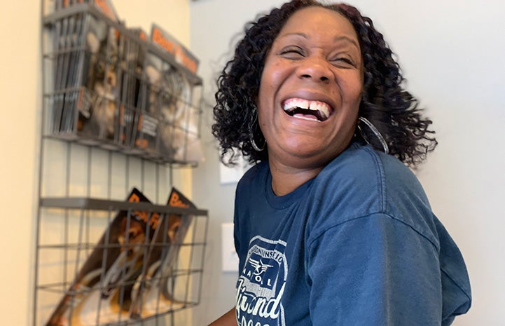 Faye Robinson smiling and laughing next to a rack of Best Friends magazines