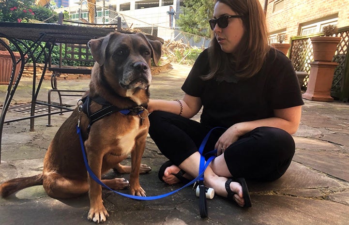 Shelby sitting next to Frank the dog on a patio