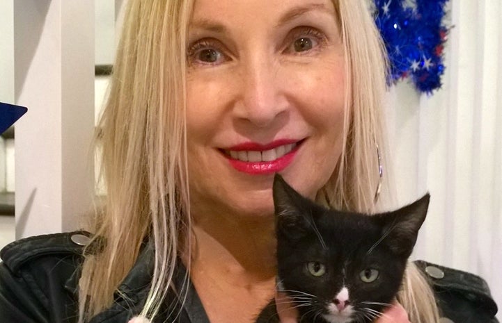 Volunteer receptionist Ruth Temple holding a black and white kitten