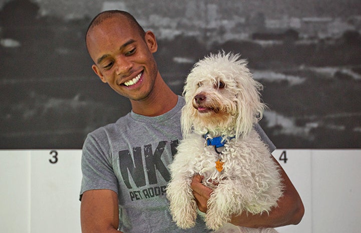 Man wearing a NKLA T-shirt holding a fluffy white dog