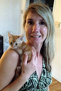 Foster mom holding an orange tabby kitten