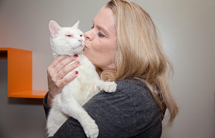 Volunteer Heather Ramsey, who fosters hospice cats, kisses a white cat