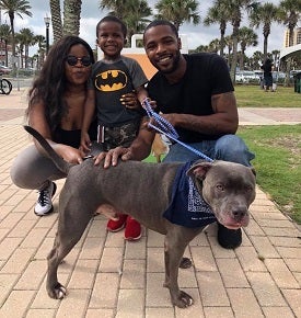 Couple with young son with gray pit bull on brick walkway