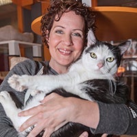 Destiny Haney holding a black and white cat that doesn't look thrilled to be having his photo taken
