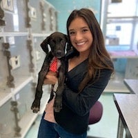 Sarah Cano in the kennels holding a black puppy
