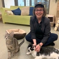 Trish Tolbert sitting on the floor with two cats