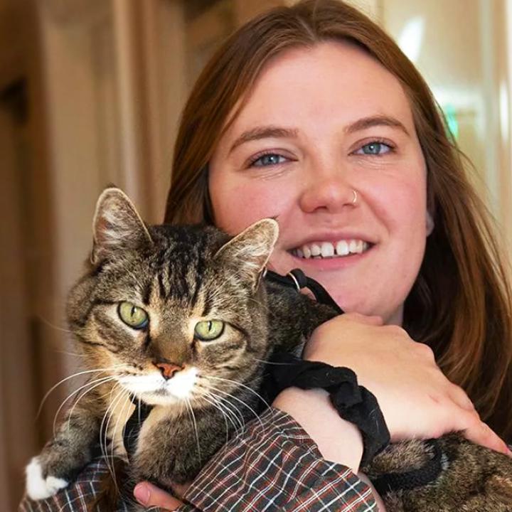 Smiling person holding a tabby and white cat