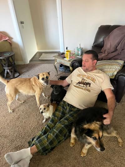 Person sitting on the floor surrounded by four dogs, including Spaghetti