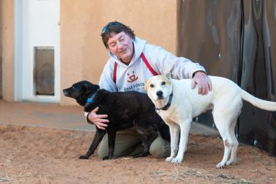 Tom the Dogtown caregiver with his arms around Hannah and Elton the dogs