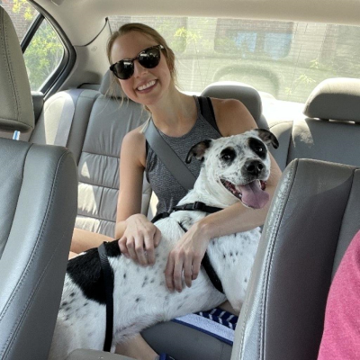 Neo the dog and a foster volunteer in the back of a vehicle