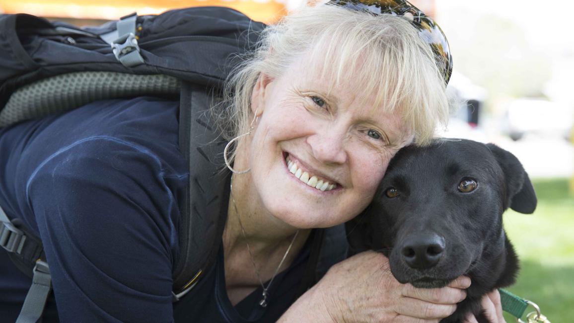 woman smiling with a black dog
