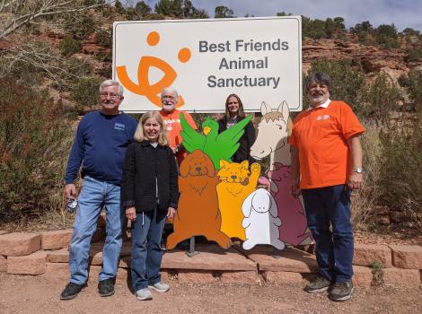 Bob and Penny Burleson with some other people standing by the sign at Best Friends Animal Sanctuary
